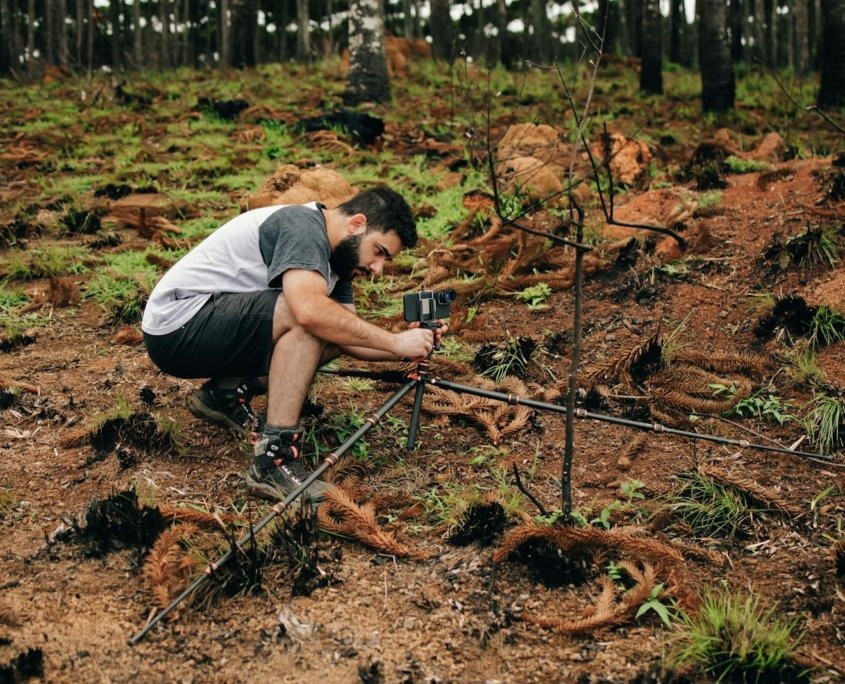 A man setting up equipment in a forest for environmental research.