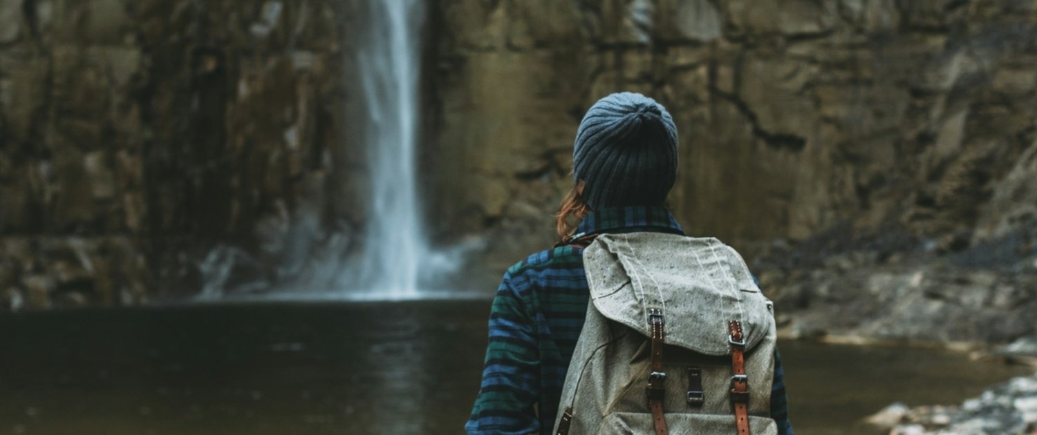 woman with backpack facing waterfalls