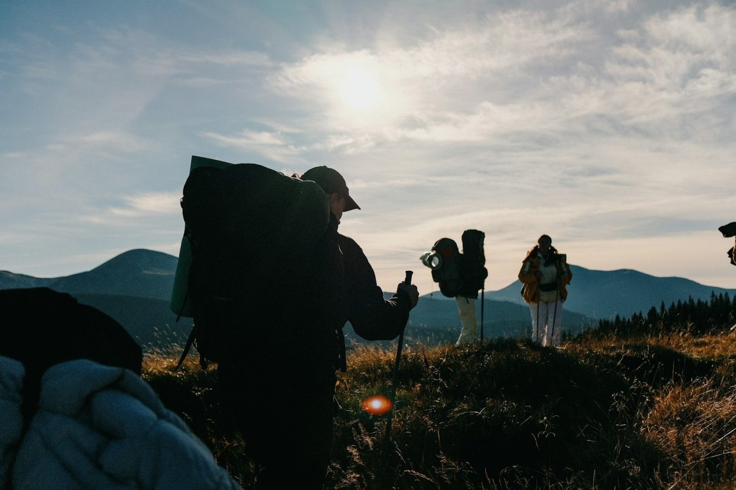 A group of people standing on top of a grass covered hillside