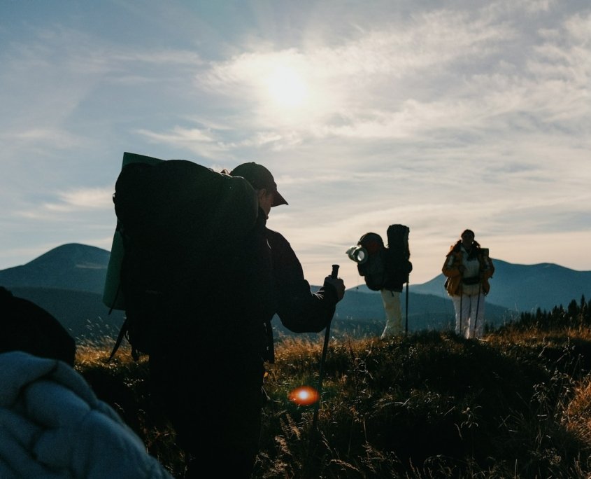 A group of people standing on top of a grass covered hillside